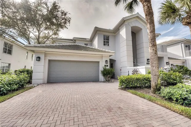 a front view of a house with yard and parking