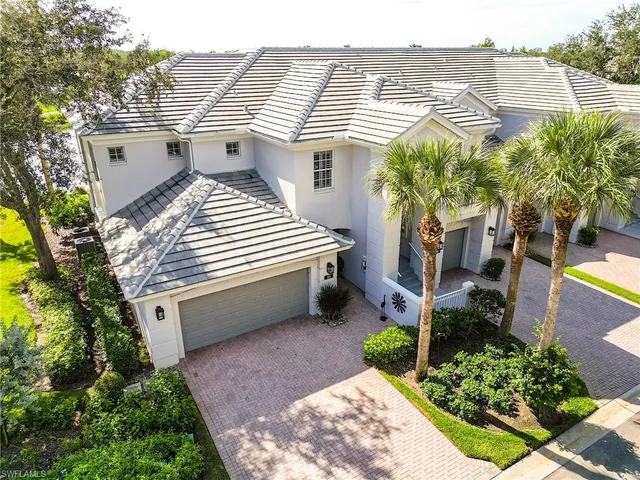 a view of a white house next to a yard with potted plants