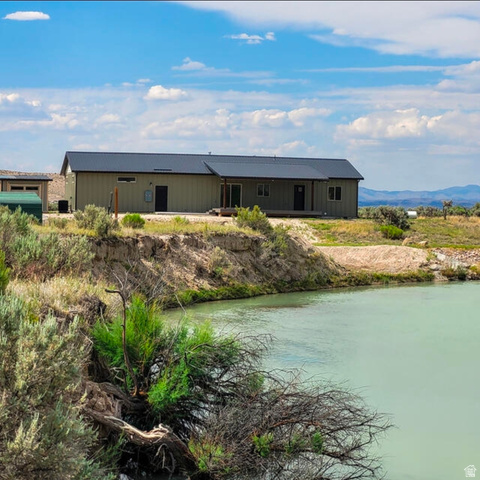 9381 South Sevier Riv Ranch Levan, UT 84639 - Photo 4 of 58 Expansive waterfront property featuring a contemporary residence with a dark metal roof, light-colored siding, and a covered porch
