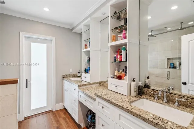 a bathroom with a granite countertop double vanity sink a shower and a mirror