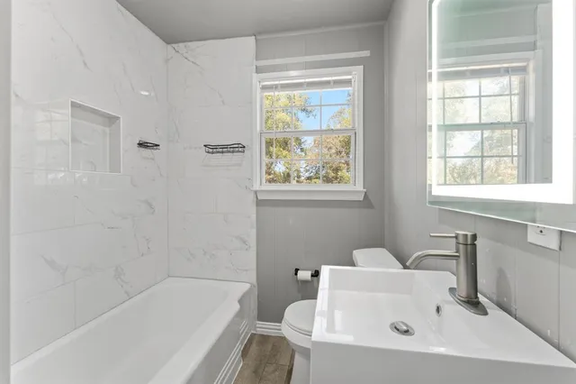a white bath tub sitting next to a white sink and a toilet