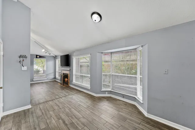 an empty room with wooden floor and windows