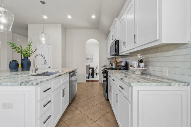 a kitchen with kitchen island granite countertop a sink and white cabinets