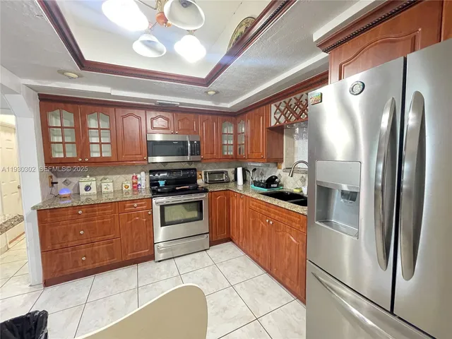 a kitchen with stainless steel appliances granite countertop a refrigerator a stove and a sink with cabinets