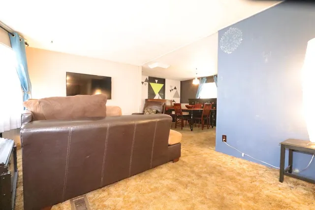 a living room with furniture a flat screen tv and a refrigerator