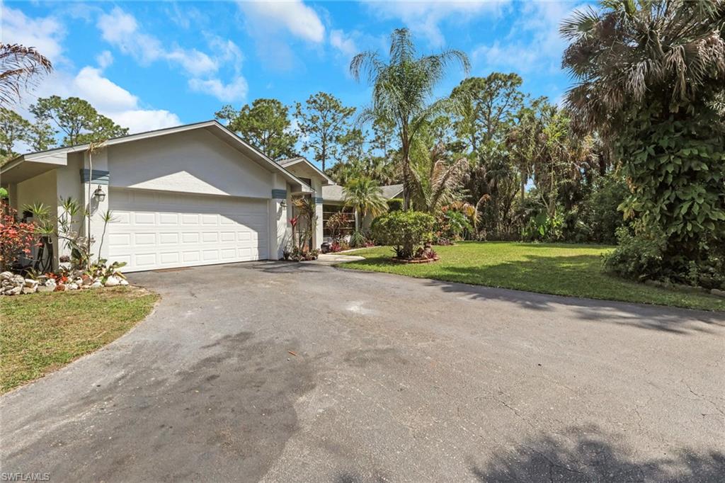 760 1st Street Northwest Naples, FL 34120 - Photo 2 of 36 a view of a house with a yard and garage