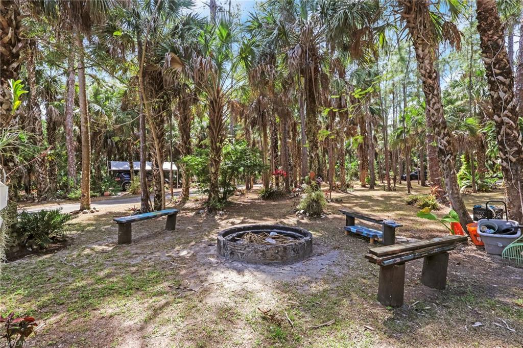 760 1st Street Northwest Naples, FL 34120 - Photo 23 of 36 a view of a backyard with lawn chairs and a fire pit