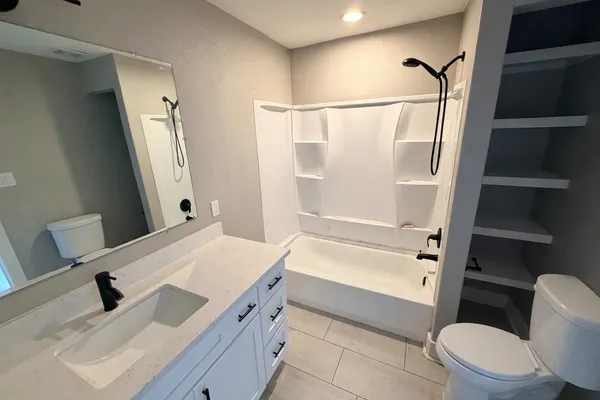 a bathroom with a sink a toilet a tub and shower