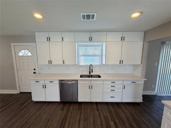 a kitchen with granite countertop a sink cabinets and wooden floor
