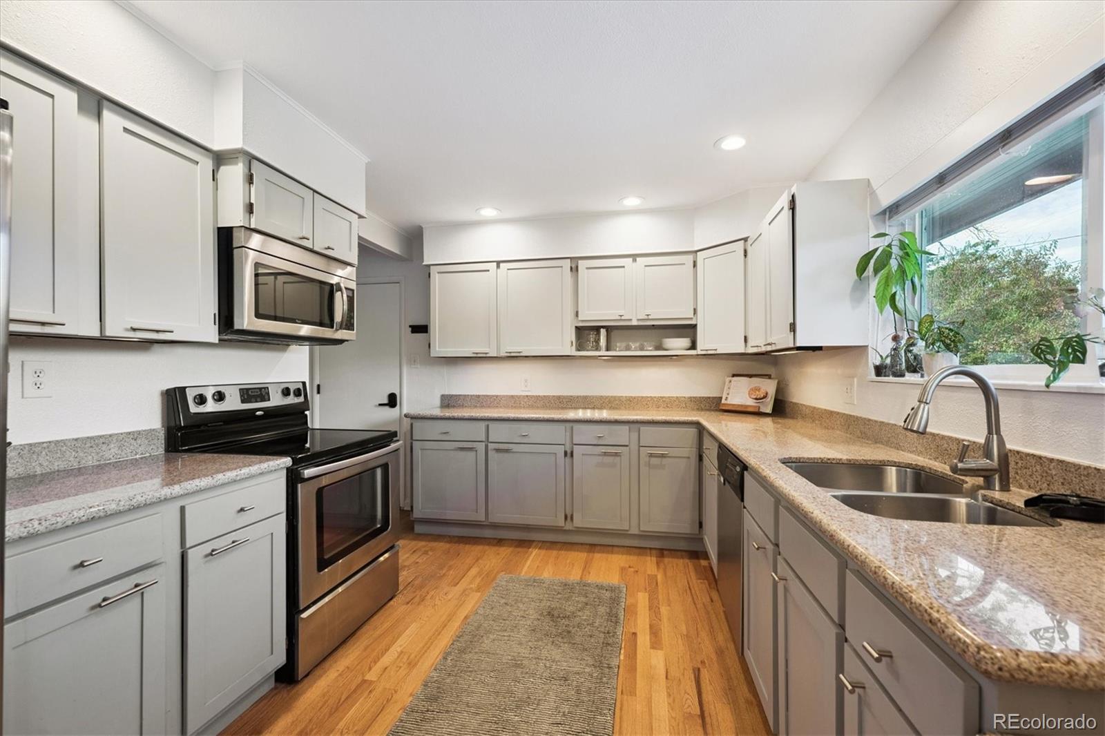 3675 South Hibiscus Way Denver, CO 80237 - Photo 14 of 50 a kitchen with stainless steel appliances granite countertop a sink stove microwave and cabinets