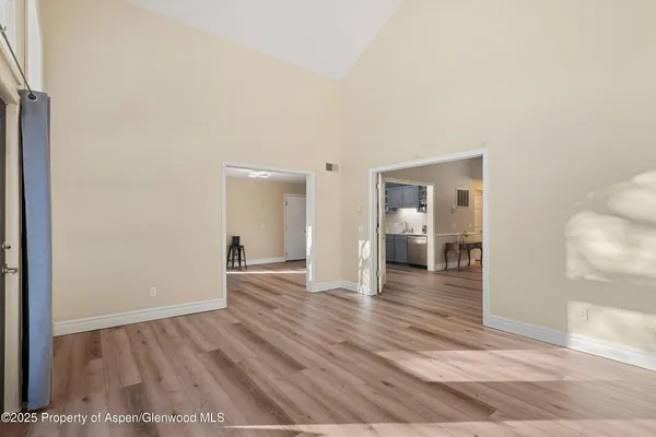 a view of a hallway with wooden floor and a bathroom