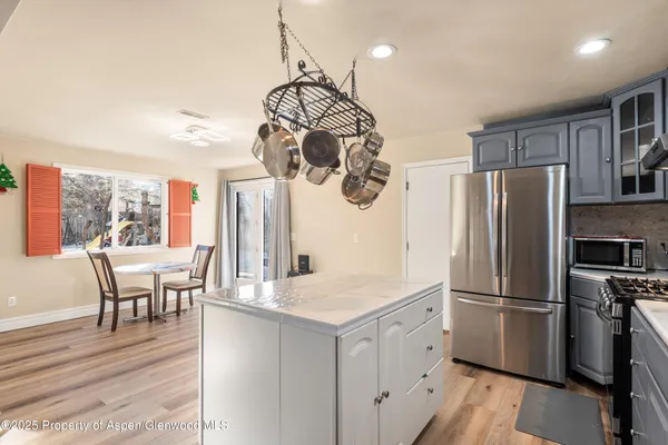 a kitchen with stainless steel appliances granite countertop a refrigerator a stove a sink dishwasher a dining table and chairs with wooden floor