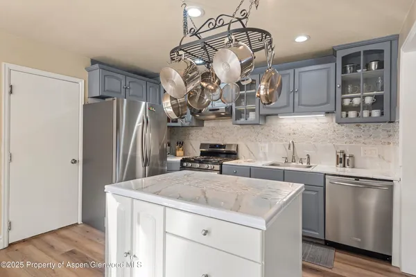 a kitchen with stainless steel appliances granite countertop a sink a stove and refrigerator