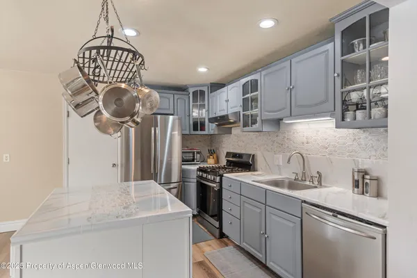 a kitchen with stainless steel appliances granite countertop a sink a stove and cabinets