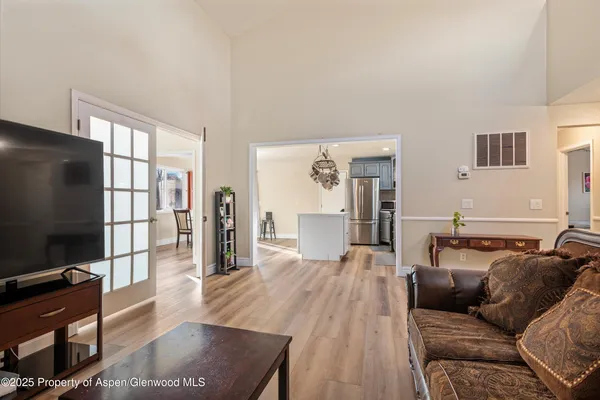 a living room with furniture a flat screen tv and a refrigerator
