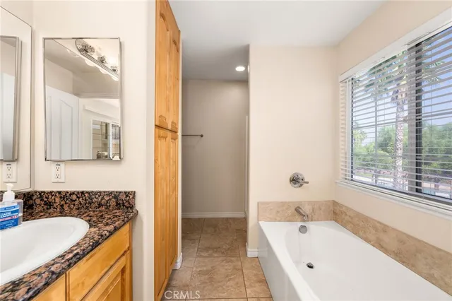a bathroom with a granite countertop tub sink and mirror