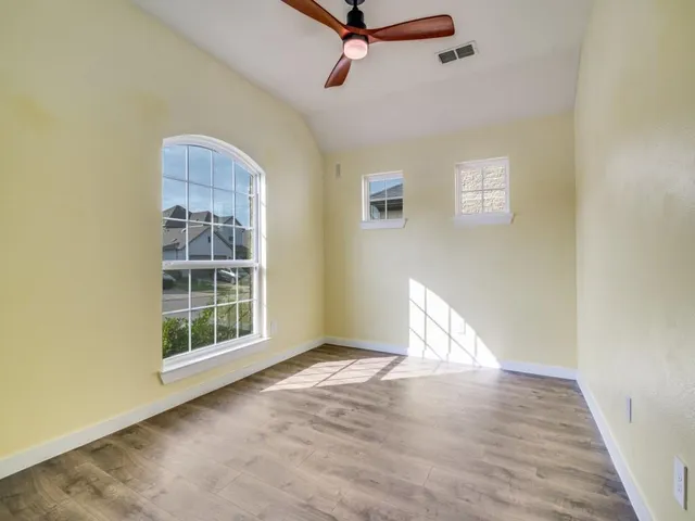 an empty room with wooden floor cabinet and windows