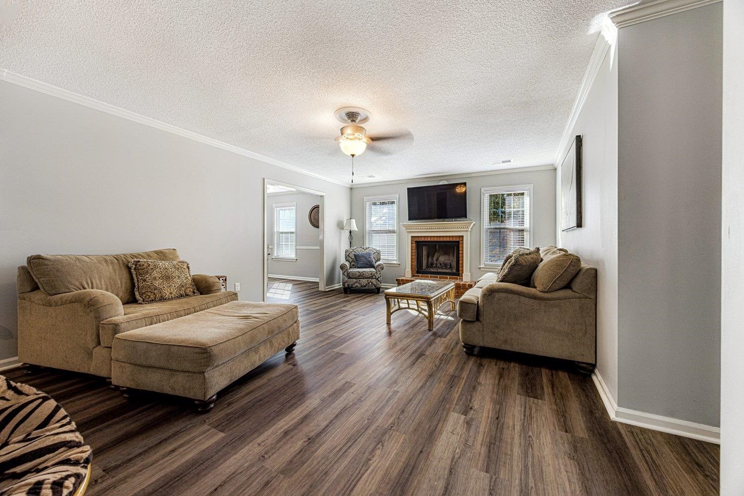 401 North Sanga Road Memphis, TN 38018 - Photo 8 of 27 Living area featuring crown molding, a brick fireplace, dark wood-type flooring, a textured ceiling, and plenty of natural light