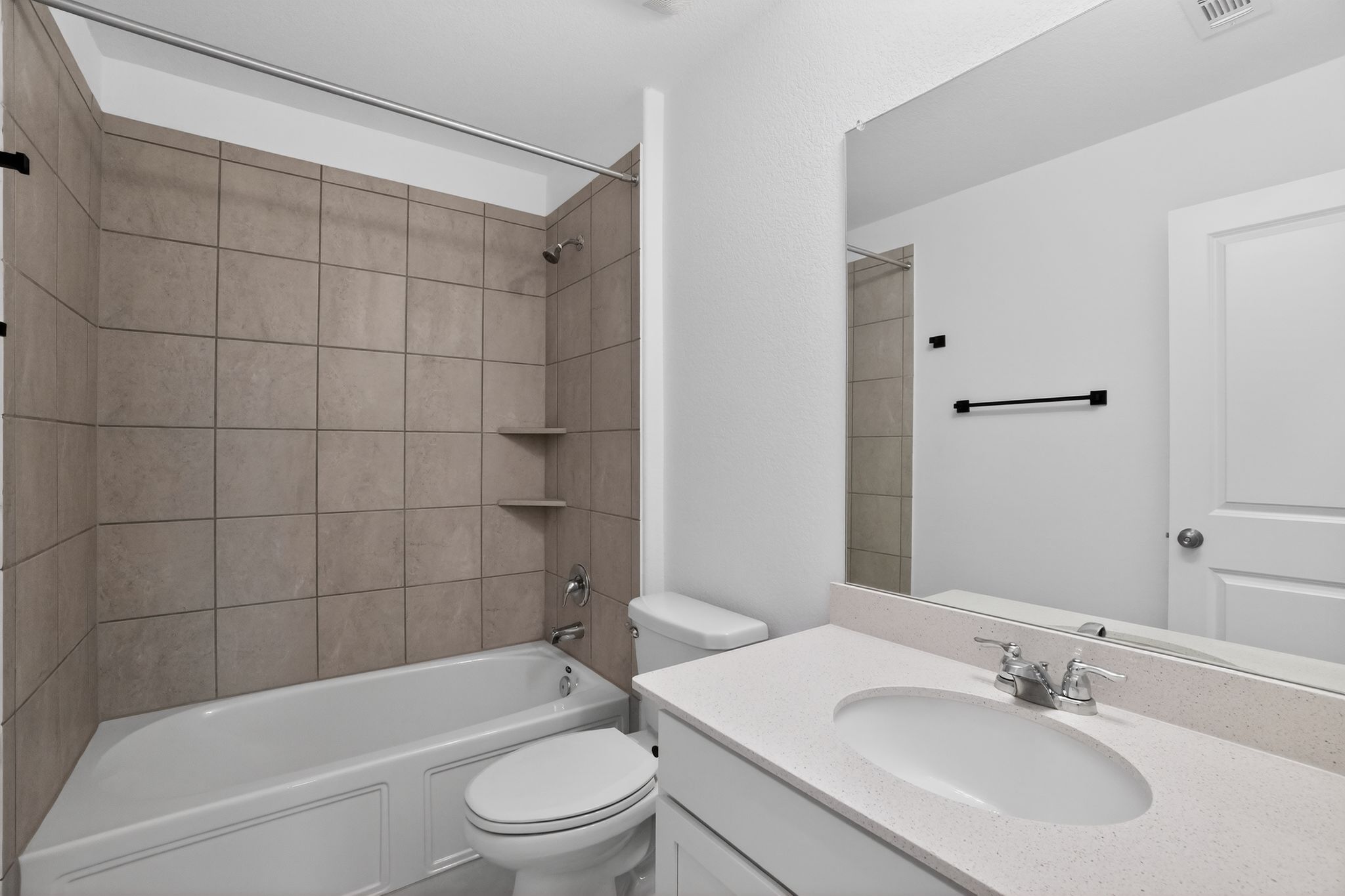 412 Perfect World Loop Jarrell, TX 76537 - Photo 11 of 15 Bathroom featuring a tiled tub/shower combination with built-in shelving, a single vanity with an integrated sink, a solid surface countertop, and a large wall-mounted mirror
