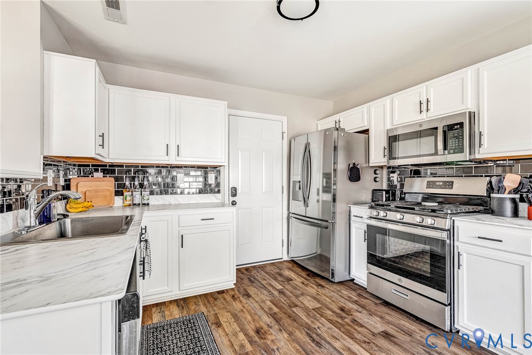 2702 Amherst Ridge Loop Colonial Heights, VA 23834 - Photo 20 of 38 a kitchen with a refrigerator stove and white cabinets