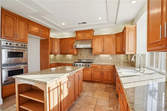 a large kitchen with kitchen island a sink a counter top space and stainless steel appliances