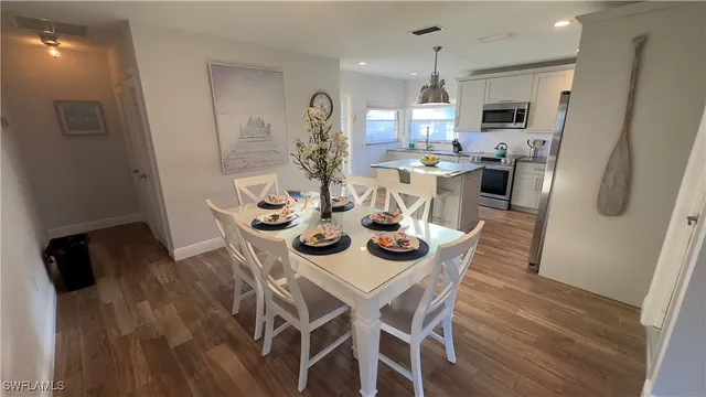 a kitchen with stainless steel appliances kitchen island granite countertop a refrigerator a stove a microwave oven a dining table and chairs with wooden floor