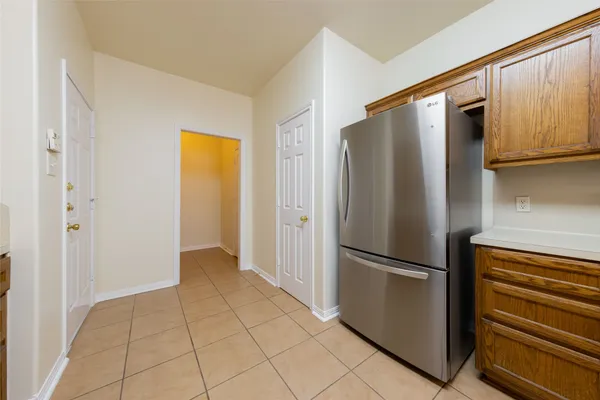 a view of a refrigerator in kitchen and an empty room with wooden floor