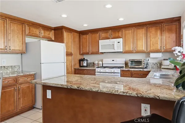 a kitchen with granite countertop a refrigerator stove top oven a sink and dishwasher