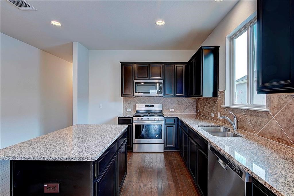 a kitchen with stainless steel appliances granite countertop stove microwave and sink