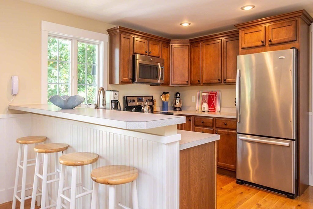 196 Springhill Road Tisbury, MA 02568 - Photo 11 of 32 a kitchen with stainless steel appliances a refrigerator a sink a stove a dining table and chairs