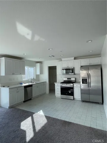 a kitchen with granite countertop a refrigerator and white cabinets