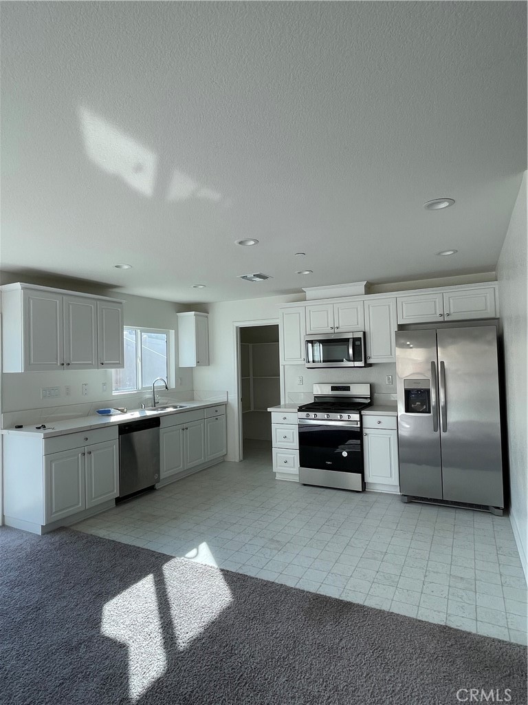 20107 Curaco Court Riverside, CA 92507 - Photo 4 of 24 a kitchen with granite countertop a refrigerator and white cabinets