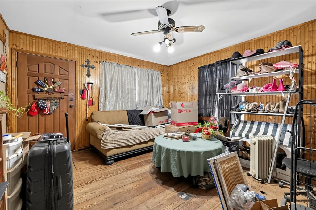 11097 County Road 137 Ranger, TX 76470 - Photo 7 of 40 Wood-paneled walls with wood-finish flooring, featuring a ceiling fan with integrated lighting and a built-in shelving unit