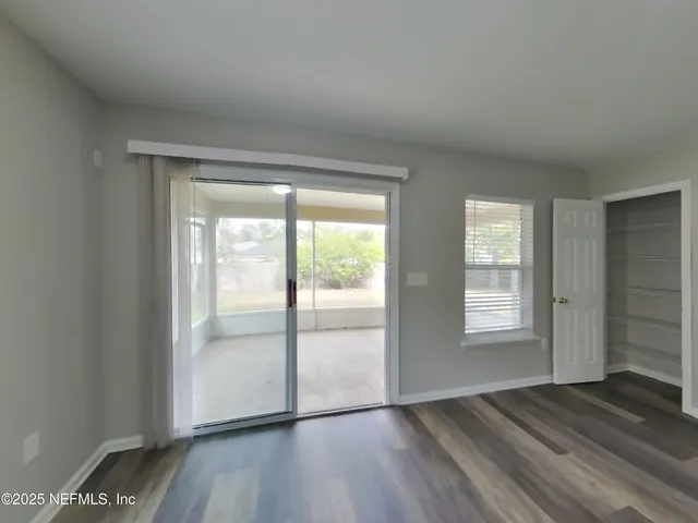 an empty room with wooden floor and windows