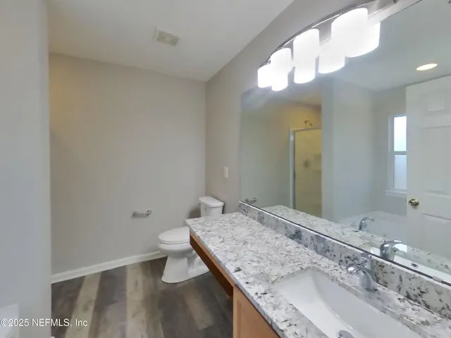 a bathroom with a granite countertop sink a large mirror and toilet