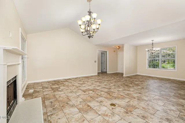 a view of an empty room with chandelier and a fireplace