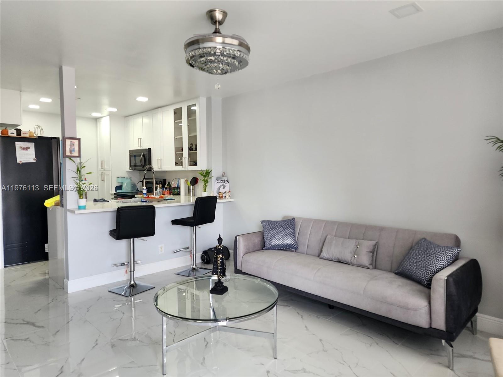 10046 Winding Lake Road, Unit 201 Sunrise, FL 33351 - Photo 4 of 12 a living room with furniture kitchen and a chandelier