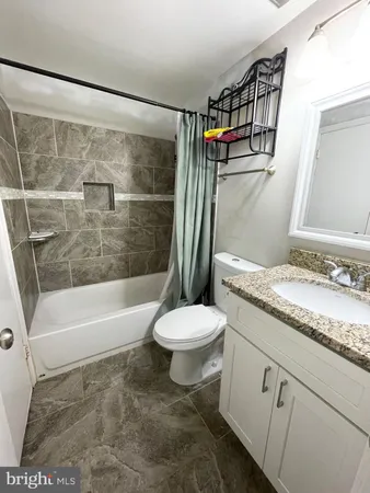 a bathroom with a granite countertop toilet sink and mirror