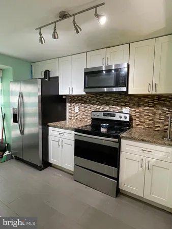 a kitchen with stainless steel appliances granite countertop a stove a refrigerator and a microwave