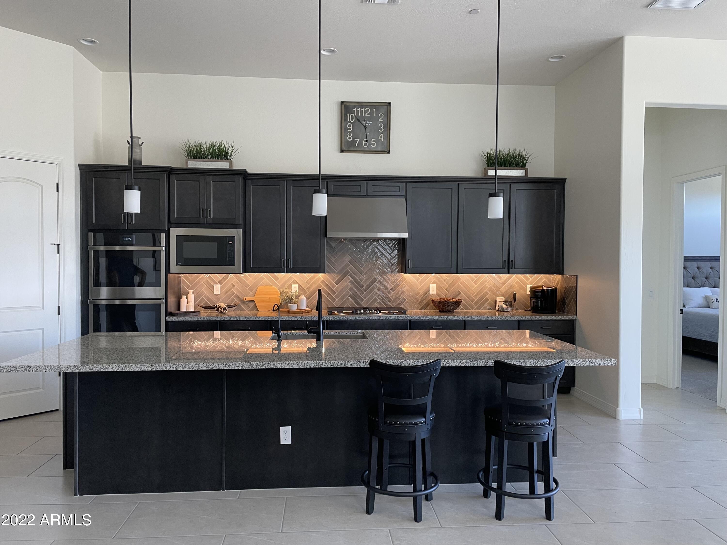 38500 North School House Road, Unit 50 Cave Creek, AZ 85331 - Photo 3 of 17 a kitchen with stainless steel appliances kitchen island granite countertop a table chairs in it and wooden floor