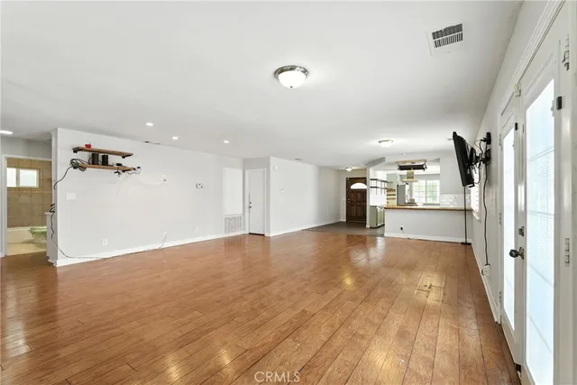 a view of a electric appliances in kitchen and empty room with wooden floor