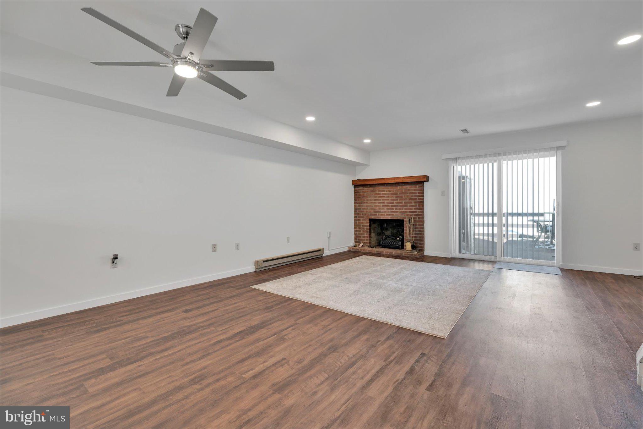 2604 Village Road Orwigsburg, PA 17961 - Photo 8 of 24 an empty room with wooden floor fireplace and windows