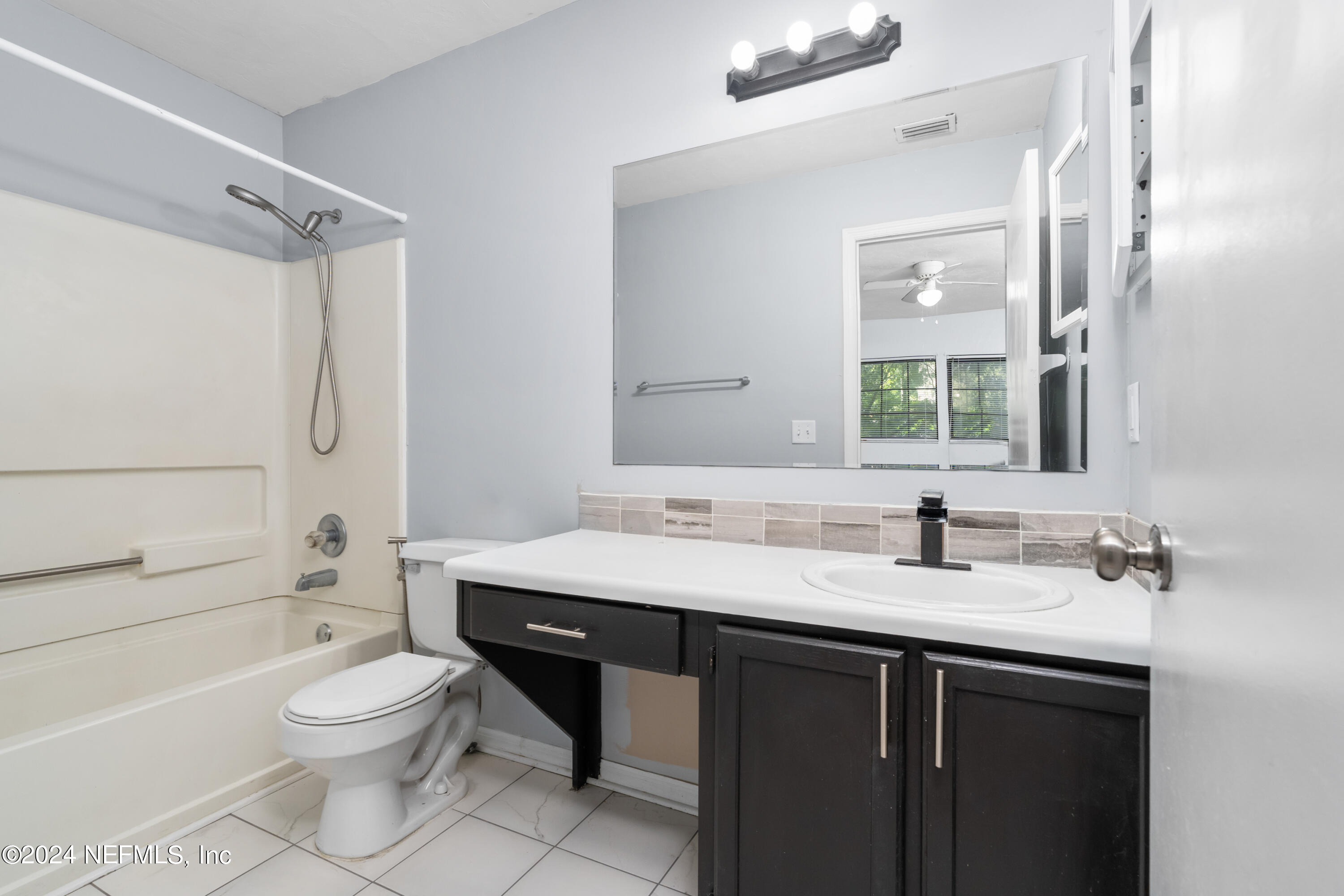 5720 Southwest 8th Place Gainesville, FL 32607 - Photo 16 of 17 a bathroom with a granite countertop sink toilet a mirror and shower
