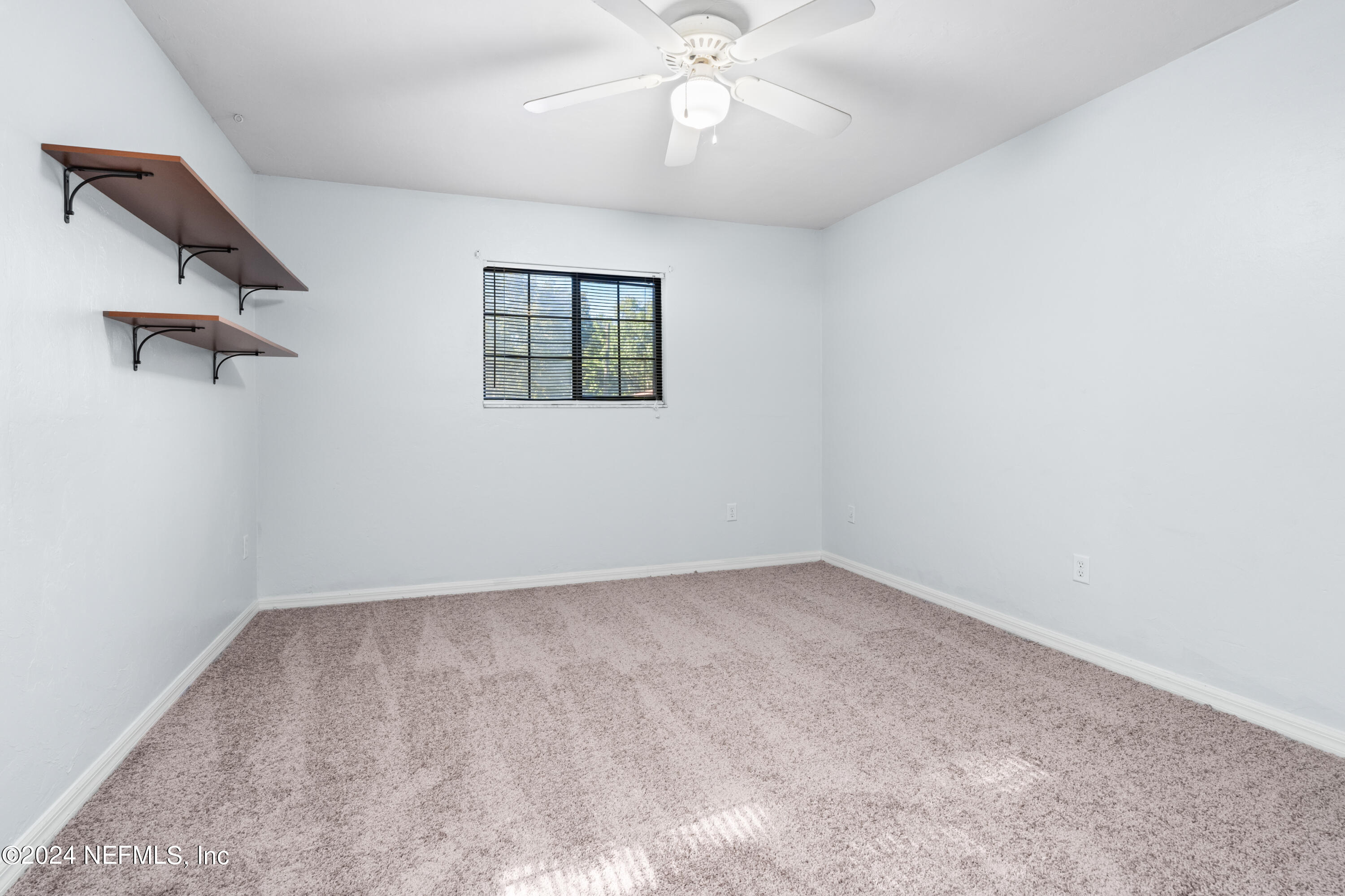 5720 Southwest 8th Place Gainesville, FL 32607 - Photo 10 of 17 an empty room with a chandelier fan and windows