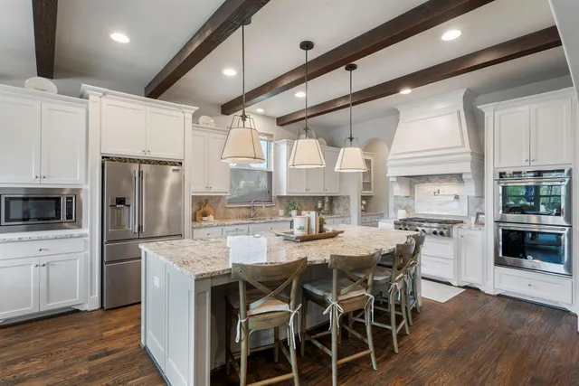 a kitchen with stainless steel appliances granite countertop a stove a sink refrigerator and a dining table with wooden floor