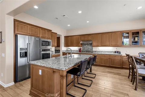 a kitchen with stainless steel appliances granite countertop a refrigerator a stove a sink a dining table and chairs