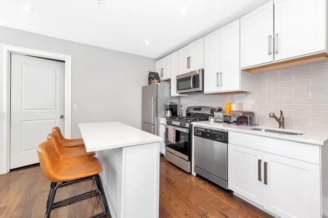 a kitchen with stainless steel appliances granite countertop a white cabinets and a refrigerator