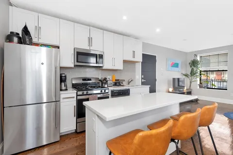 a kitchen with stainless steel appliances a refrigerator a stove a sink a dining table and chairs