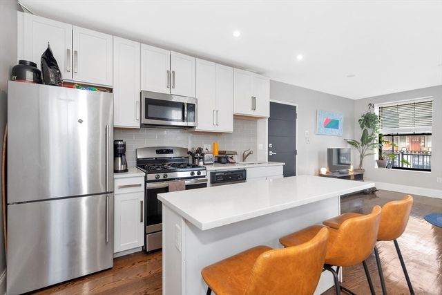 a kitchen with stainless steel appliances a refrigerator a stove a sink a dining table and chairs