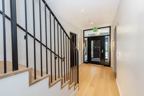 a view of a hallway with wooden floor and staircase